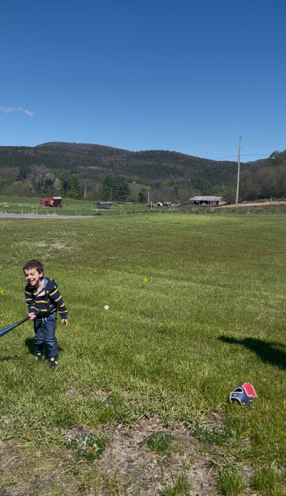 Noah practicing his swing in the field, mountain in the background