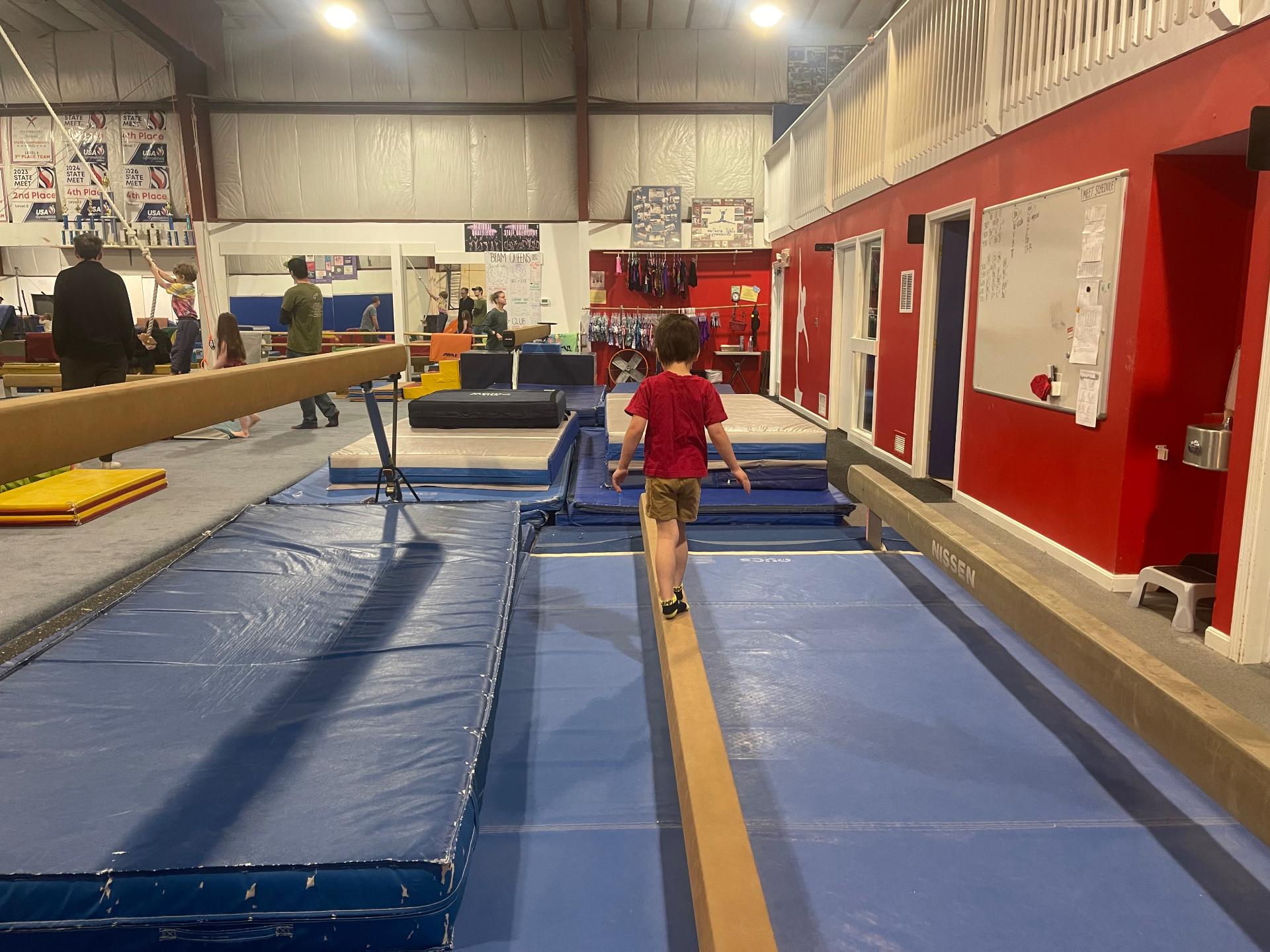 Noah walking the balance beam over blue mats