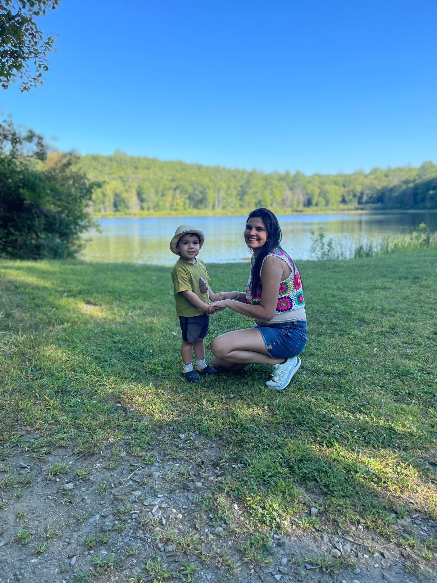 Mom and toddler by a calm lake on a sunny day