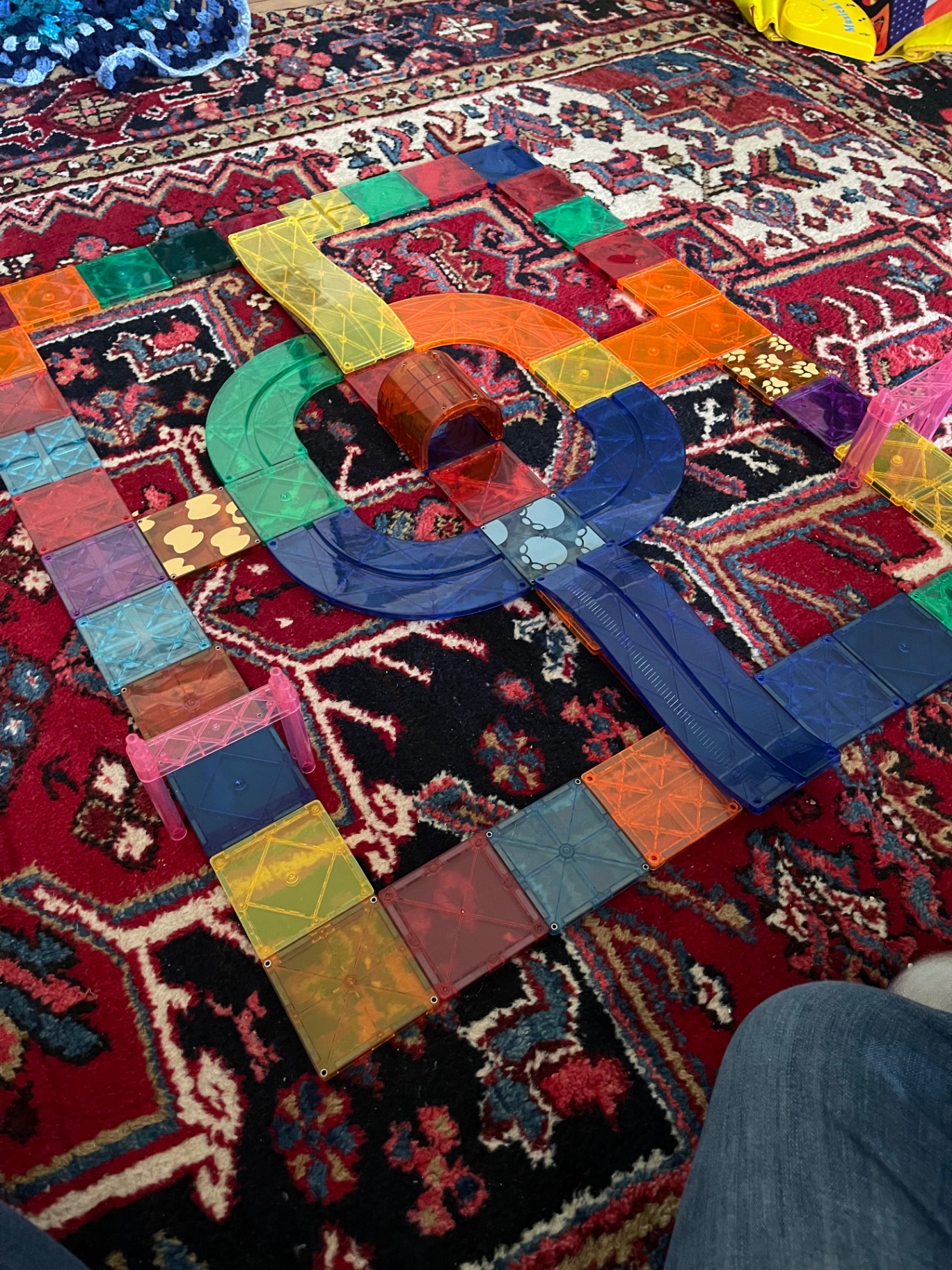 An elaborate magnatile track and tunnel layout spread across a red Persian rug